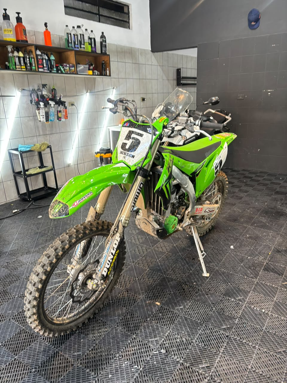 Moto verde antes do atendimento, com barro nas rodas e na carenagem